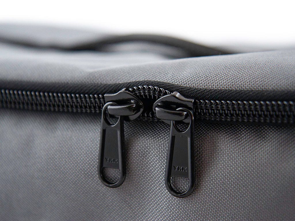 Close-up of a gray bag with black zippers on a blurred background